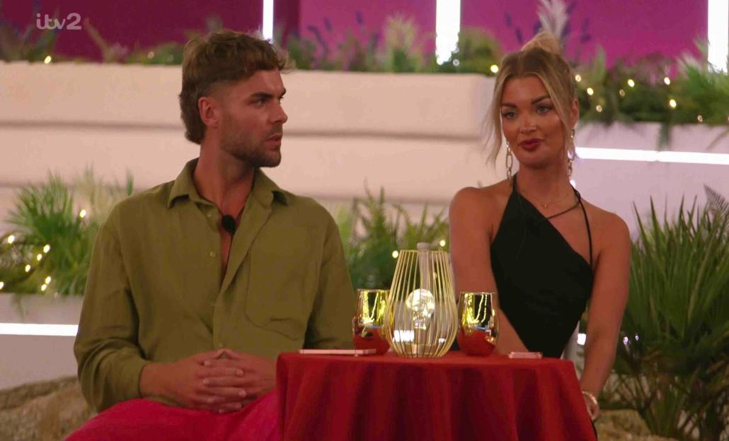 Screenshot of a man and woman sitting at a table, appearing on Love Island.