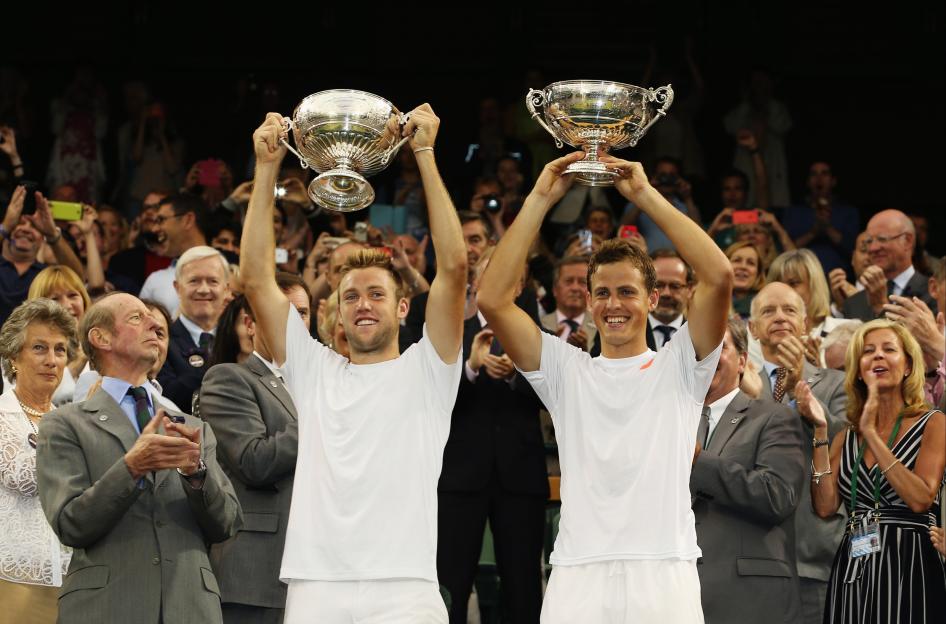 Two tennis players holding up trophies.