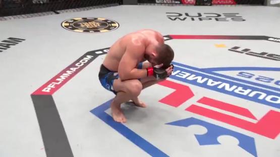 A fighter sits on the cage floor, head in hands.