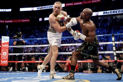 Floyd Mayweather Jr. throwing a punch at Conor McGregor during a boxing match.