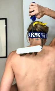 Person using a paint roller to apply something to their back.