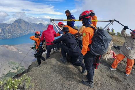 Rescue workers evacuating a person from a ravine on a mountain.