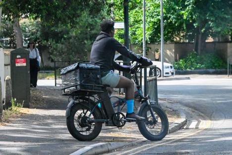 Man riding an electric bicycle with a delivery box.