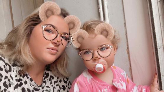 Woman and toddler wearing glasses with bear ears filter.