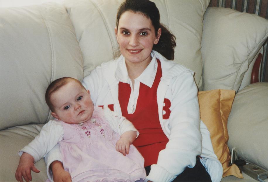 A mother and her baby daughter sitting on a couch.