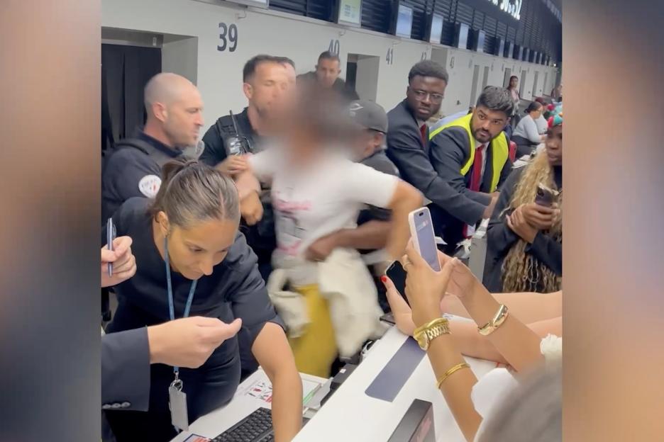 Airport security subdues a disruptive passenger.
