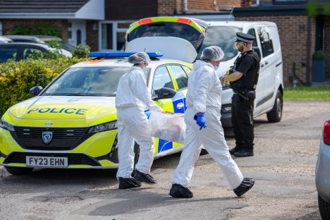 Crime scene investigators in protective suits at a murder scene.