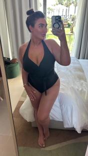 Woman in black swimsuit taking a selfie.