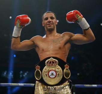 Kal Yafai, victorious boxer, holding up his championship belt.