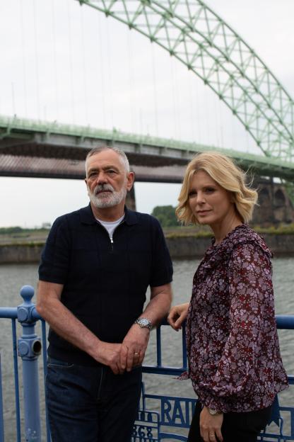 David Wilson and Emilia Fox standing by a bridge.