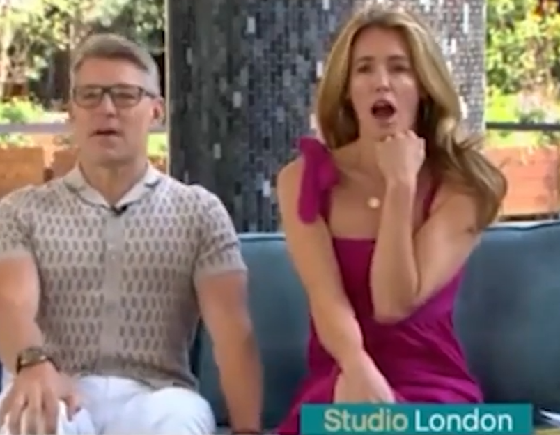 Two people sitting on a couch, a woman in a pink dress and a man in a patterned shirt.