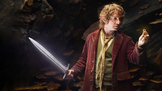 Martin Freeman as Bilbo Baggins holding the One Ring and Sting.