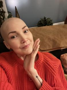 Woman with shaved head and red sweater.