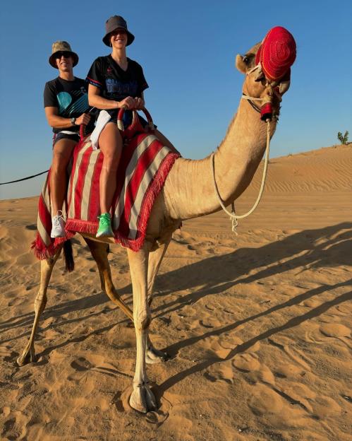 Two people riding a camel in the desert.
