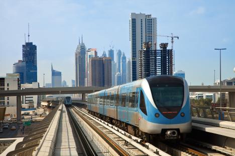 Dubai Metro train on elevated tracks with skyscrapers in the background.