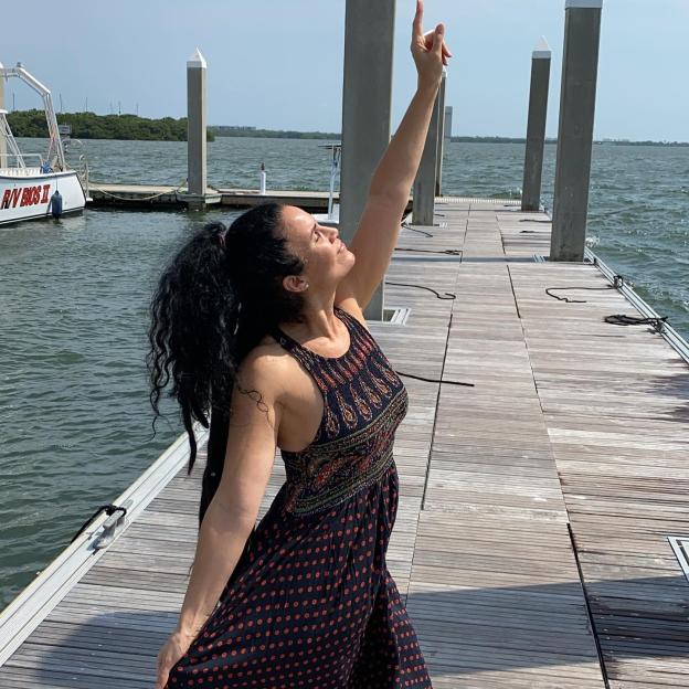 Woman with arm raised on a dock.