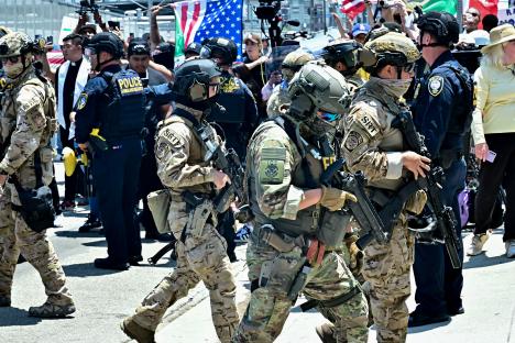 Law enforcement officers in tactical gear during a protest.