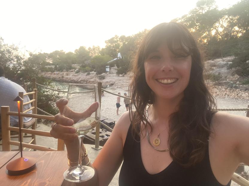 Woman holding a glass of wine at a seaside restaurant.