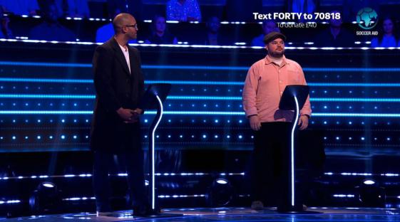 Two men standing at podiums on a game show set.