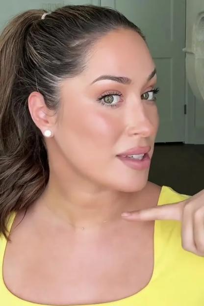 Woman demonstrating where to apply bronzer for a lifted jawline.