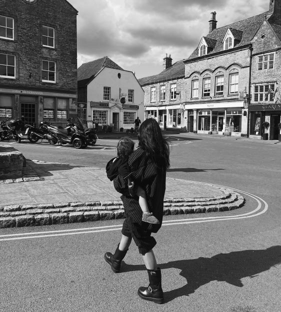 A person carrying a child walks through a town square.