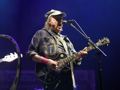 Neil Young playing guitar on stage.