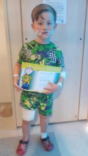 Boy holding bravery award after dog attack.