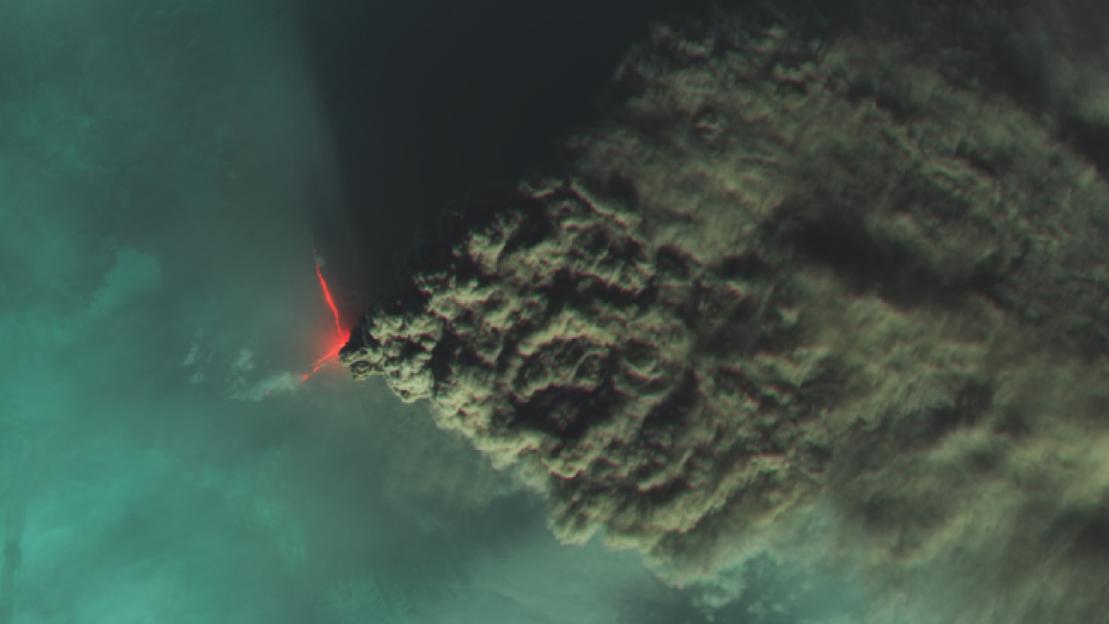 Aerial view of volcanic eruption with lava and ash plume.