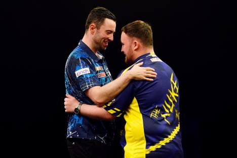 Luke Humphries and Luke Littler embracing at a darts tournament.