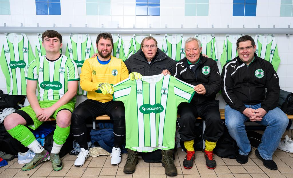 Harry Redknapp and Tunley Athletic FC team members in a changing room with a new team jersey.