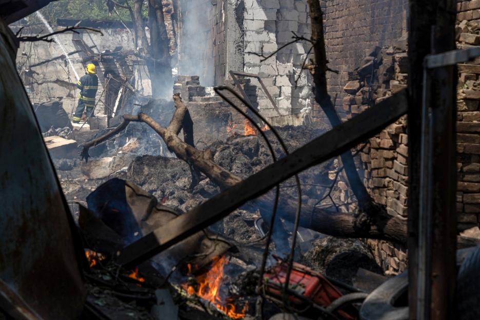 A Ukrainian firefighter extinguishes a fire in a damaged stable.