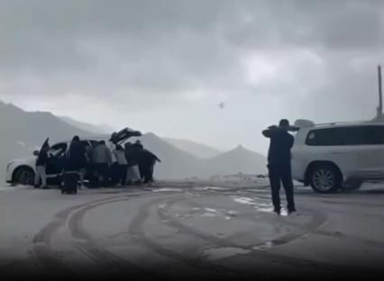 People pushing a car back from the edge of a cliff.