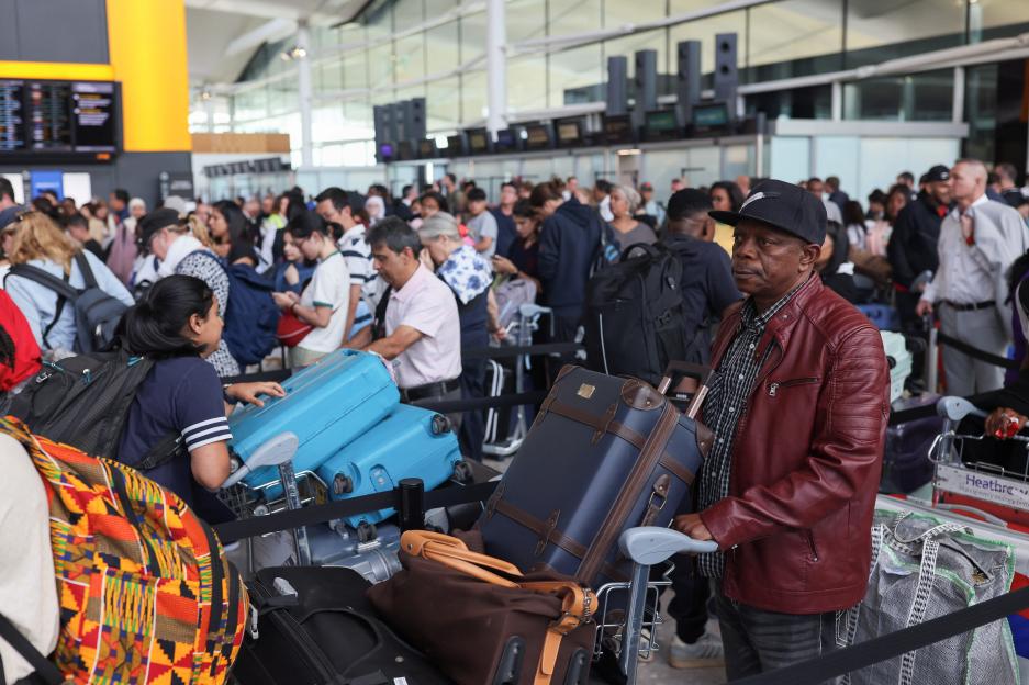 Passengers waiting in line at Heathrow Airport with luggage.