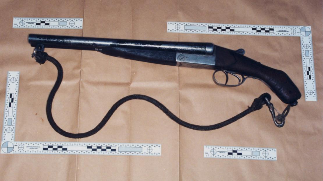 Sawn-off shotgun with cord, next to a scale.