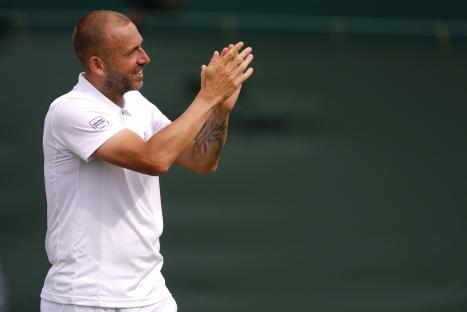Dan Evans applauding after winning a tennis match.