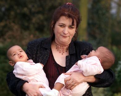 Woman holding six-month-old twin girls.