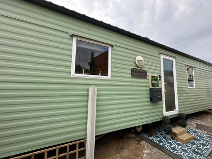 A light green mobile home with a sign that says