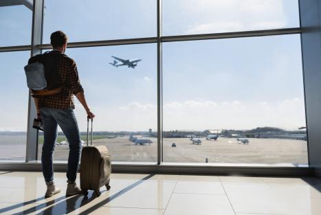 Man at airport watching airplane take off.
