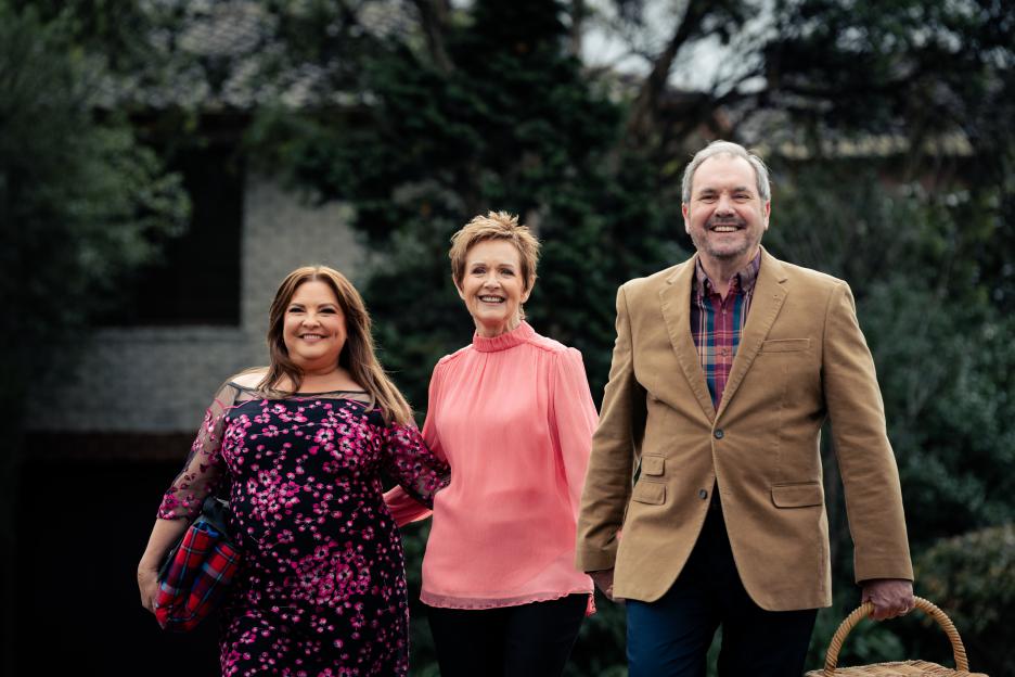 Three people walking outdoors holding hands.
