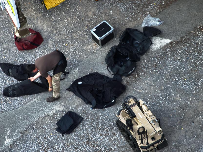 Bomb disposal robot and officer preparing equipment at a counter-terrorism operation.
