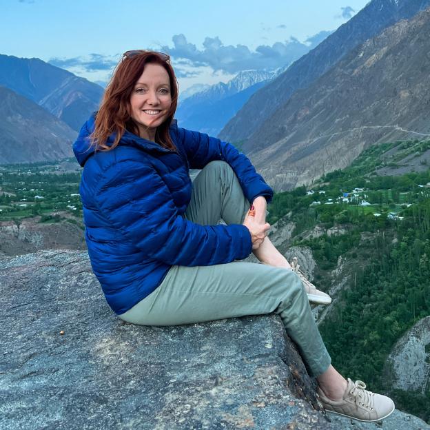 Woman sitting on a rock overlooking a mountain valley.