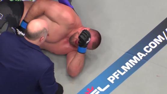 A knocked-out MMA fighter lying on the mat.