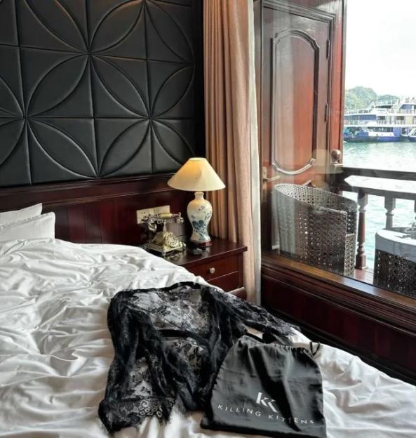 Black lace robe and Killing Kittens bag on a bed in a luxury cabin overlooking the water.