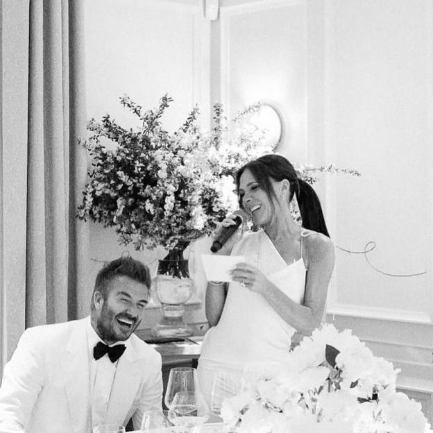 Black and white photo of David and Victoria Beckham at a wedding anniversary celebration. Victoria is giving a speech.