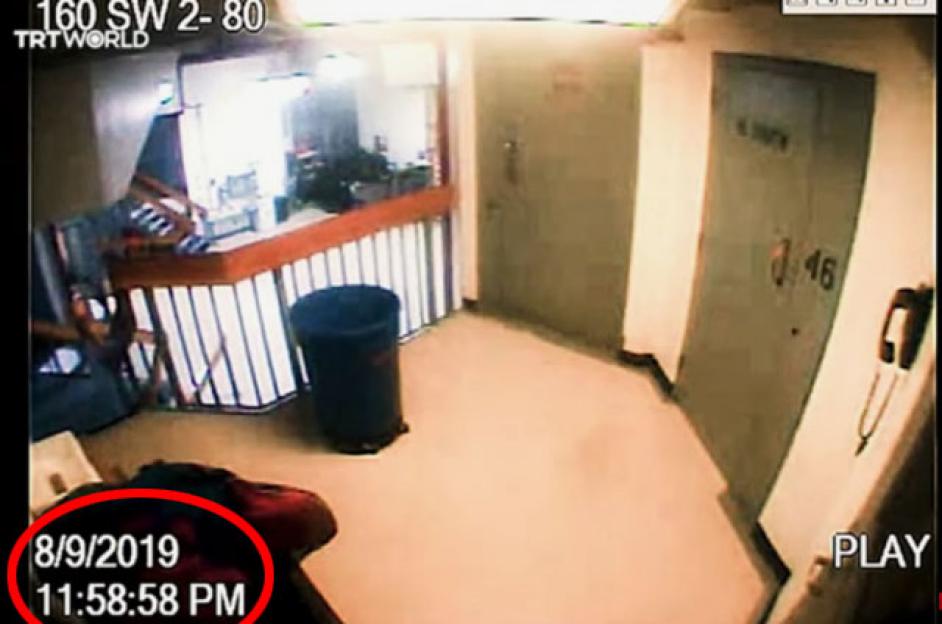 Security camera footage of a hallway with a trash can and stairs.