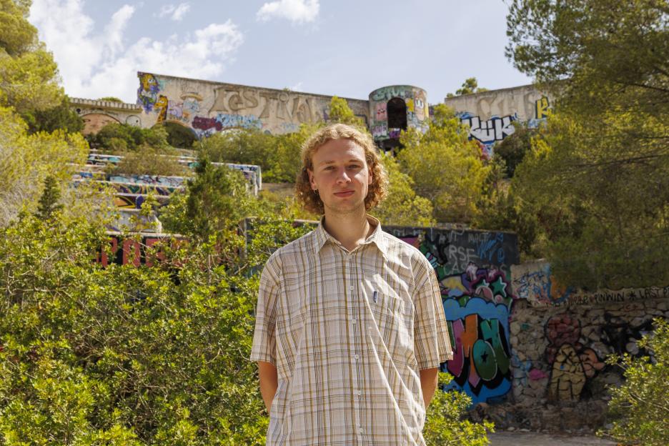 Man standing in front of graffiti-covered ruins.