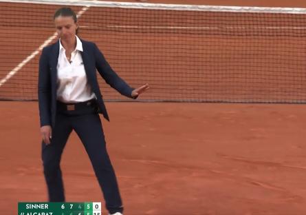Tennis umpire signaling on a clay court.