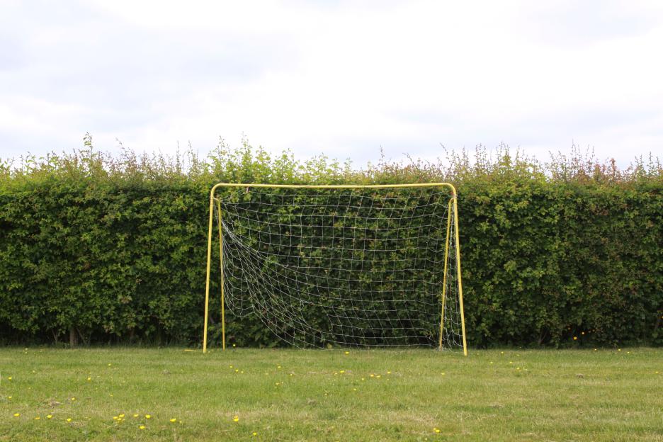 Yellow soccer goal in a garden.