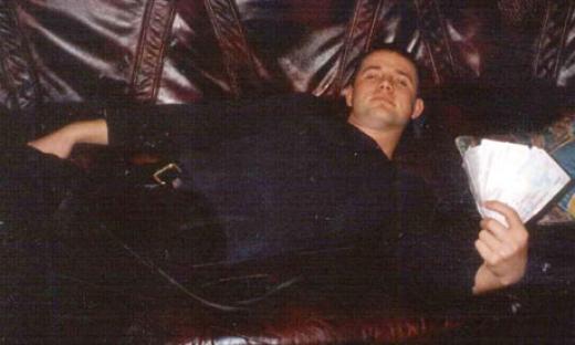 Man reclining on a couch with a large amount of cash.