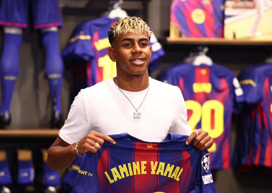 Lamine Yamal holding his FC Barcelona jersey.